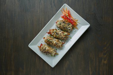 Yeşillik, havuç dilimleri, hafif dikdörtgen bir tabak üzerinde biber ile ev yapımı tavuk göğsü rulo. Asya mutfağı kavramı. Koyu ahşap arka plan. Metin için alan.