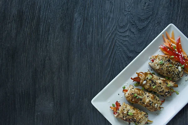 Petto di pollo fatto in casa rotoli con verdure, fette di carota, peperone su un piatto rettangolare leggero. Il concetto di cucina asiatica. Fondo in legno scuro. Spazio per testo . — Foto Stock