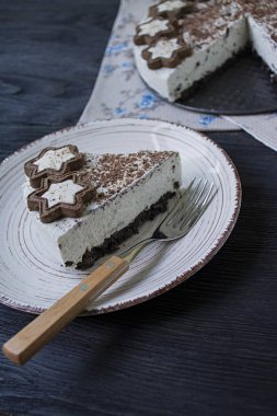 Süzme peynirli kek (pişmiş cheesecake olmadan) kurabiye ve koyu ahşap arka plan üzerinde rendelenmiş siyah çikolata ile dekore edilmiştir.
