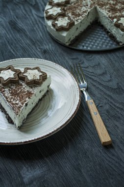 Süzme peynirli kek (pişmiş cheesecake olmadan) kurabiye ve koyu ahşap arka plan üzerinde rendelenmiş siyah çikolata ile dekore edilmiştir.