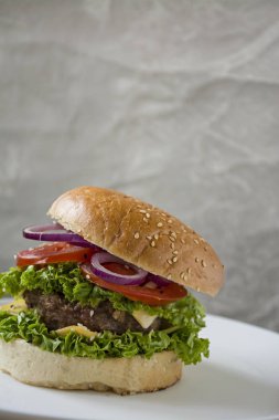 Beyaz tabakta taze ev yapımı burger. Sağlıksız gıda.