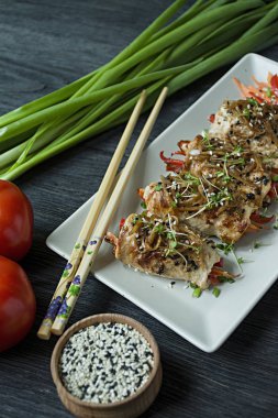 Yeşil, havuç dilimleri, karanlık bir kesme tahtasında biber ile taze tavuk göğsü ile Rolls. Sağlıklı ev yapımı gıda kavramı. Koyu ahşap arka plan.