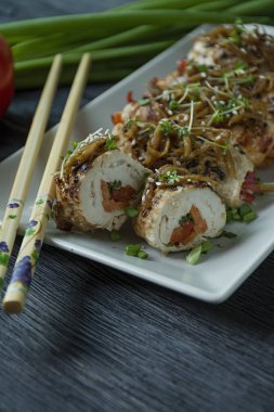 Yeşil, havuç dilimleri, karanlık bir kesme tahtasında biber ile taze tavuk göğsü ile Rolls. Sağlıklı ev yapımı gıda kavramı. Koyu ahşap arka plan.