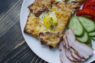 Koyu ahşap arka plan üzerinde yumurta, sebze ve pastırma ile ızgara sandviç. Lezzetli kahvaltı.