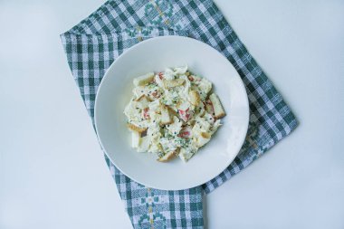 Kraker, yengeç çubukları, tavuk fileto, taze otlar ve mayonez tereyağı ile deneyimli sert peynir ile salata beyaz bir plaka servis. Mayonez salatası. Yukarıdan görüntüle. Beyaz arka plan.