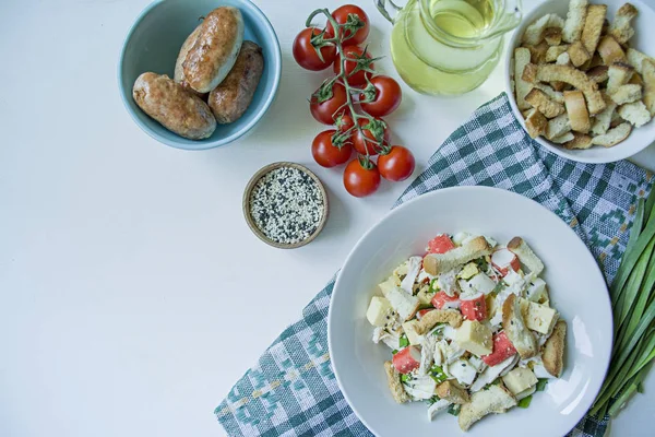 Salat mit Crackern, Krabbenstangen, Hühnerfilet, frischen Kräutern und Hartkäse, gewürzt mit Mayonnaise-Butter, serviert auf einem weißen Teller. Salat mit Mayonnaise. Blick von oben. weißer Hintergrund. — Stockfoto