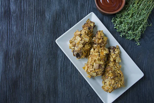 Bacchette di pollo arrosto su un piatto. Cosce di pollo impanate, pollo fritto. Sfondo in legno scuro . — Foto Stock