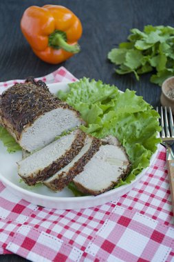 Yeşil salata ile beyaz bir plaka dilimlenmiş baharatlar pişmiş haşlanmış domuz. Koyu ahşap arka plan.