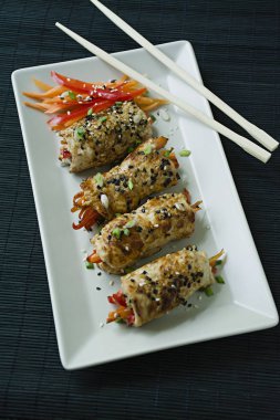 Yeşil, havuç dilimleri, karanlık bir kesme tahtasında biber ile taze tavuk göğsü ile Rolls. Sağlıklı ev yapımı gıda kavramı. Koyu ahşap arka plan.