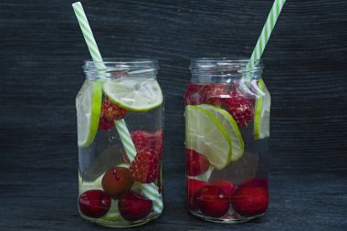 Meyve ile ferahlatıcı yaz içeceği. Kiraz, ahududu, limondan yapılmış içecek. Koyu ahşap arka plan.