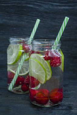 Meyve ile ferahlatıcı yaz içeceği. Kiraz, ahududu, limondan yapılmış içecek. Koyu ahşap arka plan.