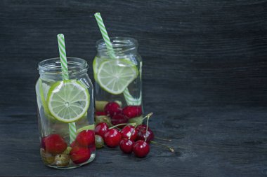 Meyve ile ferahlatıcı yaz içeceği. Kiraz, bektaşi üzümü, limondan yapılmış içecek. Koyu ahşap arka plan. Metin için alan.