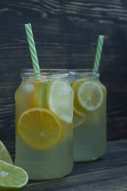 Narenciye serinletici yaz içeceği. Limon, limon, portakal iç. Koyu ahşap arka plan.