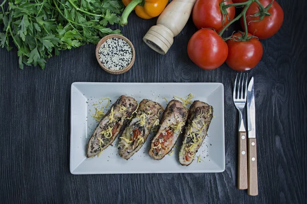 Baked chicken rolls with cheese, greens served on a white plate. Fresh vegetables. Dark wooden background. — Stock Photo, Image