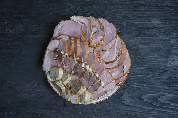 Meat platter with a choice - cutting sausages and cured meat on the holiday table. Dark wooden background.