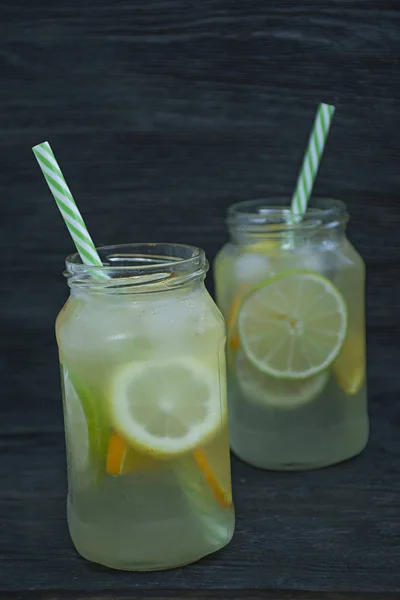 Refreshing summer drink from citrus fruits. Drink from lime, lemon, orange. Dark wooden background.