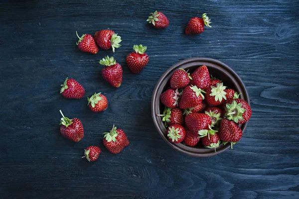 Fresas frescas en un plato sobre un fondo de madera oscura . —  Fotos de Stock