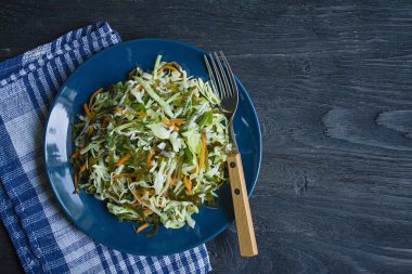 Beyaz lahana salatası, deniz lahanası ve zeytinyağı, dereotu ve maydanoz ile terbiyeli taze havuç. Koyu ahşap arka plan.