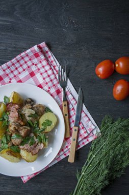 Et ve sebze ile fırında genç patates. Koyu ahşap arka plan.