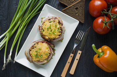 Pastırma dilimleri ile pişmiş kıyılmış peynir, yeşillik. Koyu ahşap arka plan.