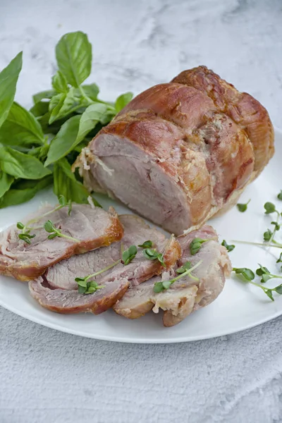 Baked pork roll with greens served on a white plate. Light background. — Stock Photo, Image