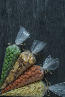 Bira, fındık ve kraker için atıştırmalıklar. Bira atıştırmalıkları selofan içinde paketlenir. Koyu ahşap arka plan.