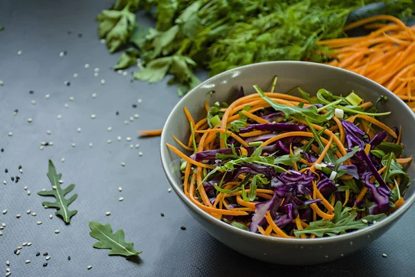 Ensalada de col roja, zanahorias y verduras. Decorado con verduras y hierbas en rodajas. Cortando tiras. Fondo oscuro . —  Fotos de Stock