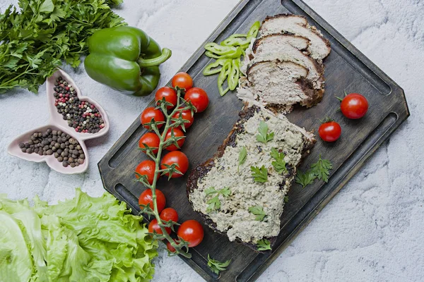 Baked pork chopped in a walnut and mint sauce on a cutting board with fresh herbs and vegetables. Light background. — Stock Photo, Image