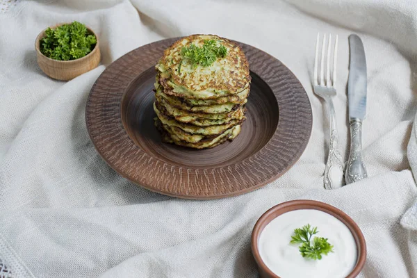 Frittelle di zucchine, frittelle di zucchine vegetariane, servite con erbe fresche e panna acida, vista dall'alto. Sfondo chiaro . — Foto Stock