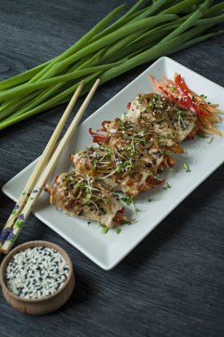 Yeşil, havuç dilimleri, karanlık bir kesme tahtasında biber ile taze tavuk göğsü ile Rolls. Sağlıklı ev yapımı gıda kavramı. Koyu ahşap arka plan.