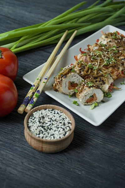 Yeşil, havuç dilimleri, karanlık bir kesme tahtasında biber ile taze tavuk göğsü ile Rolls. Sağlıklı ev yapımı gıda kavramı. Koyu ahşap arka plan.