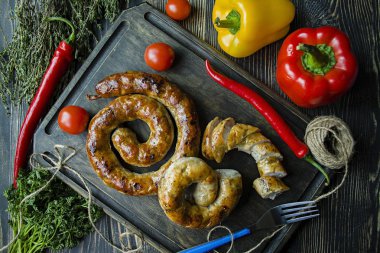 Kızarmış sosis otlar ve Baharatlar, ahşap arka plan ile. Ve ev yapımı sosis pişmiş halka. Ahşap bir gemide bir çatal, otlar ve sebze ile servis. Yukarıdan görüntülemek.