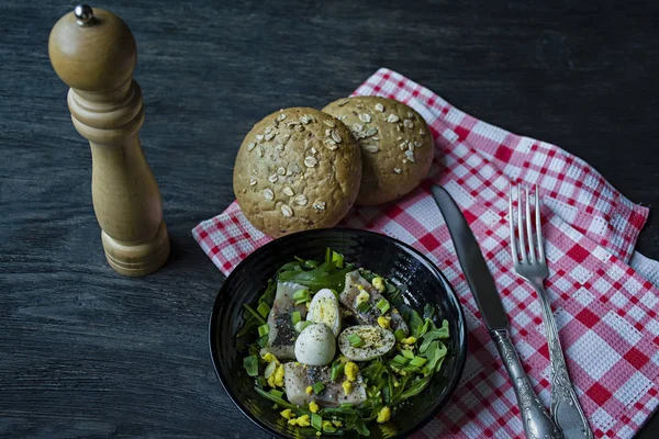 Marinierter Hering mit Rucola, Zwiebeln, gekochten Wachteleiern und Zitronensaft und Olivenöl. leckerer Salat. Richtige Ernährung. dunkler Holzhintergrund. — Stockfoto