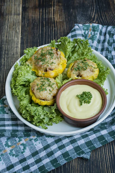 Baked Patty Pan Squash stuffed with meat and cheese, greens. Wood background.