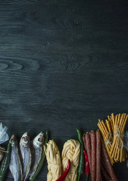 Snacks til øl, nødder og kiks. Ølsnacks er pakket i cellofan. Mørk træbaggrund. Plads til tekst . - Stock-foto