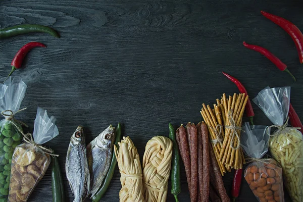 Snacks til øl, nødder og kiks. Ølsnacks er pakket i cellofan. Mørk træbaggrund. Plads til tekst . - Stock-foto