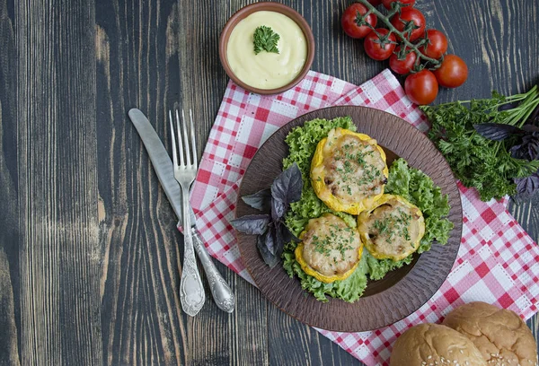 Baked Patty Pan Squash stuffed with meat and cheese, greens. Wood background.
