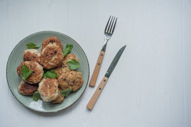 Beyaz ahşap arka plan üzerinde bir tabak üzerinde servis otlar ile Cutlets.