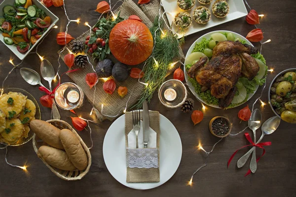 Thanksgiving dinner. Halloween dinner. Festive table with chicken and all side dishes, pumpkin, autumn leaves and seasonal autumn decor. The table is decorated with a garland, top view. — Stock Photo, Image