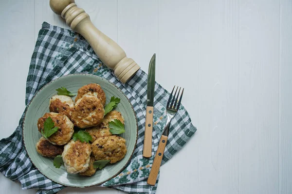 Beyaz ahşap arka plan üzerinde bir tabak üzerinde servis otlar ile Cutlets.