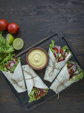 Meksika yemeği. Ahşap bir arka plan üzerinde tavuk ve sebze yakın çekim ile sarılmış burrito. Metin için alan.