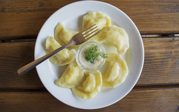 Dumplings op een witte plaat met zure room. -Traditioneel Oekraïens eten. — Stockfoto