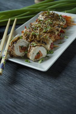 Yeşil, havuç dilimleri, karanlık bir kesme tahtasında biber ile taze tavuk göğsü ile Rolls. Sağlıklı ev yapımı gıda kavramı. Koyu ahşap arka plan.