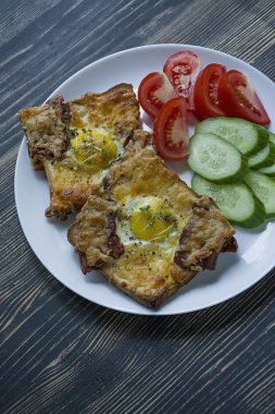 Koyu ahşap arka plan üzerinde yumurta, sebze ve pastırma ile ızgara sandviç. Lezzetli kahvaltı.