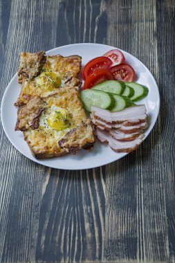 Koyu ahşap arka plan üzerinde yumurta, sebze ve pastırma ile ızgara sandviç. Lezzetli kahvaltı.