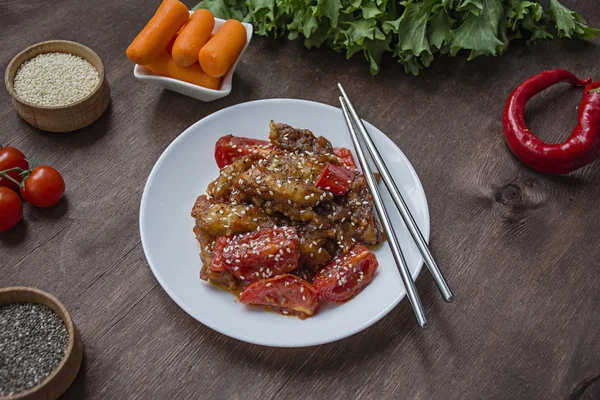 Salada de berinjela e tomate de estilo coreano quente com sementes de gergelim e ervas. Comida asiática. Prato vegetariano. Fundo de madeira. Lugar para texto . — Fotografia de Stock