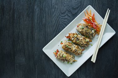 Yeşil, havuç dilimleri, karanlık bir kesme tahtasında biber ile taze tavuk göğsü ile Rolls. Sağlıklı ev yapımı gıda kavramı. Koyu ahşap arka plan.