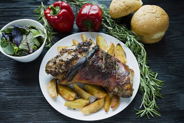 Patates ile kızarmış domuz eti beyaz bir tabak üzerinde hizmet vermiştir. Taze Bulgar biber, biberiye ile dekore edilmiştir. Koyu ahşap arka plan. Yukarıdan görüntüle.