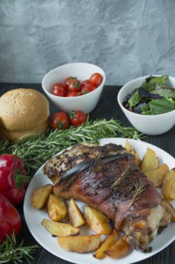 Beyaz tabakta servis edilen kızarmış domuz inciği ve patates. Fırında domuz eti. Koyu ahşap arka plan. Yukarıdan görüntüle.