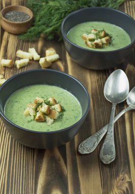 Kremalı ıspanak çorbası, kraker, bitki ve chia tohumları. Ahşap bir masada bir kasede servis edilen yeşil çorba. Düz yatıyordu.